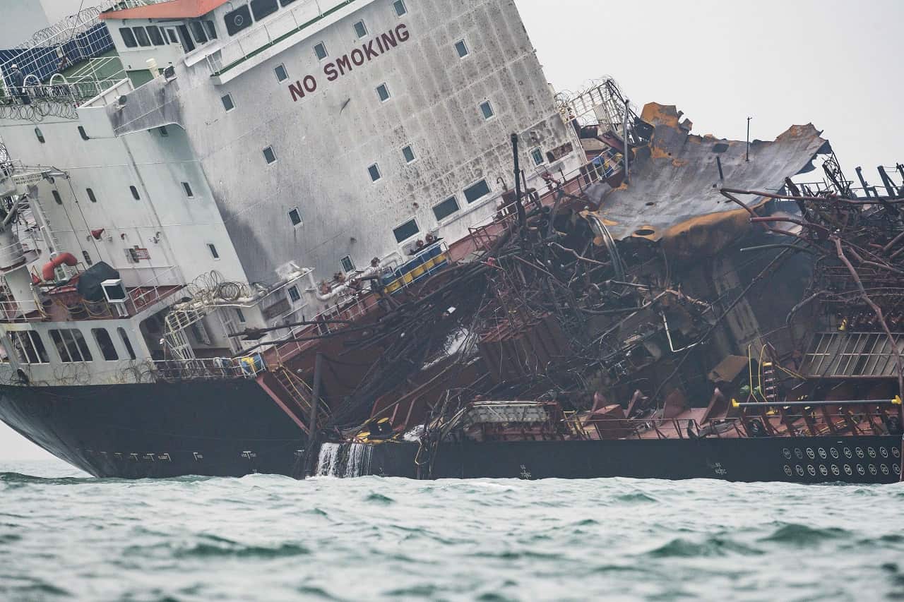 The damaged oil tanker is seen tilting to one side.