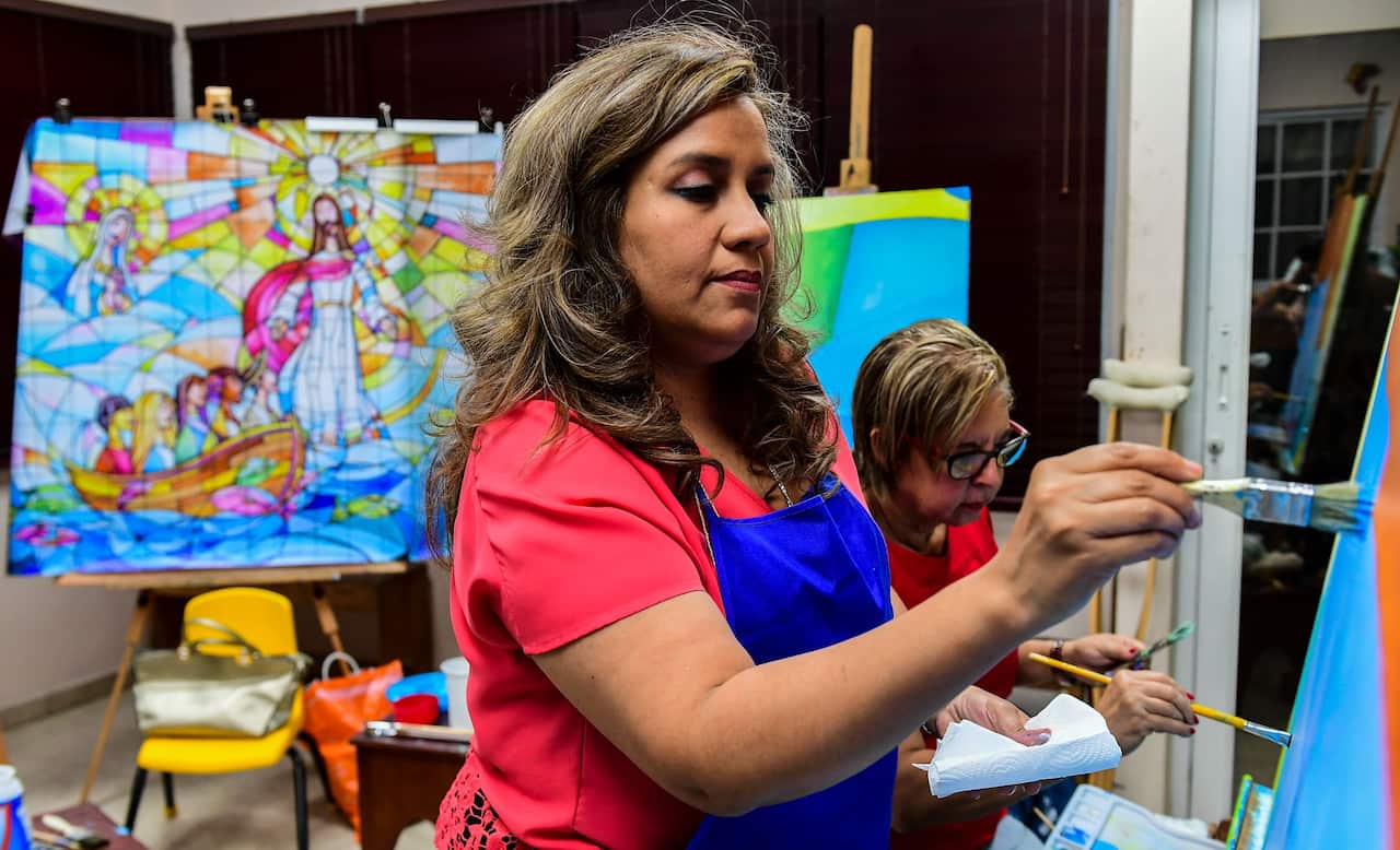 A student of Ecuadoran artist Ivan Delgado works on a panel of the wall against racism. 
