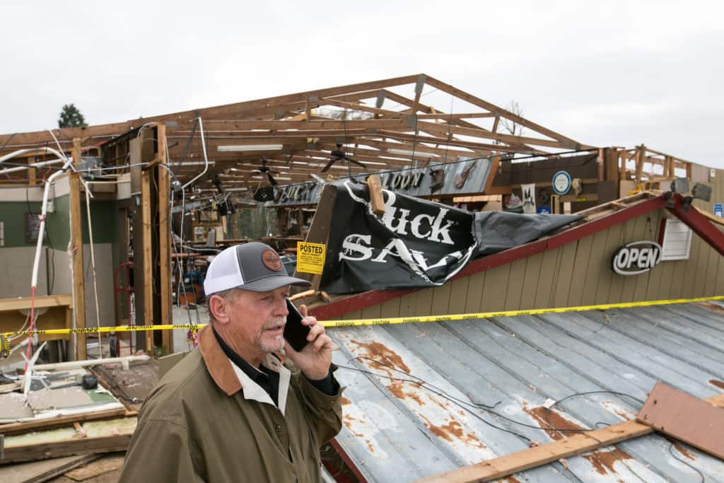 David McBride, owner of Buck Wild Saloon, talks on the phone in front of his bar after it was destroyed.