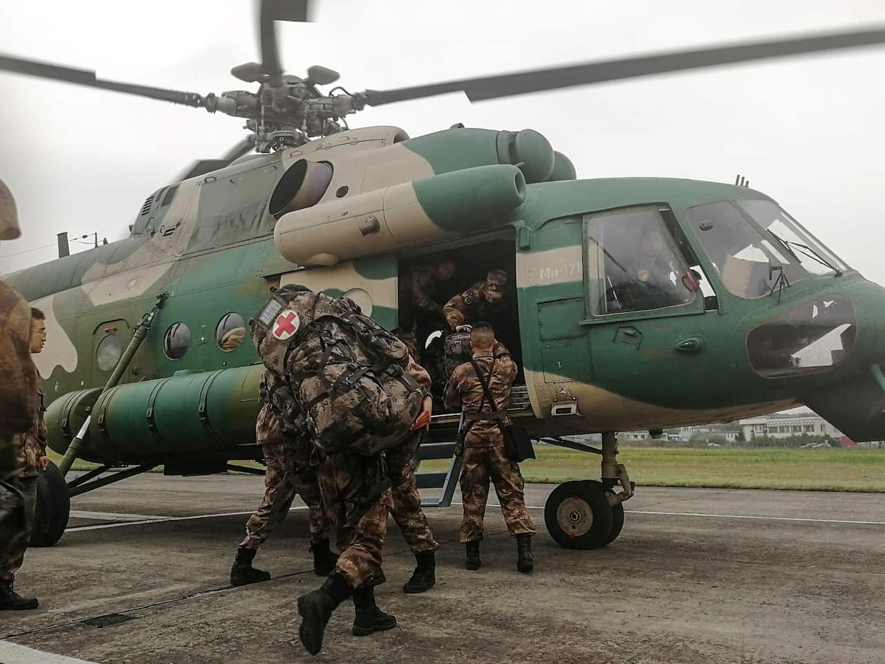Chinese soldiers board on a helicopter in China's southwestern Sichuan province, preparing to rescue firefighters trapped by a forest blaze in Muli County.