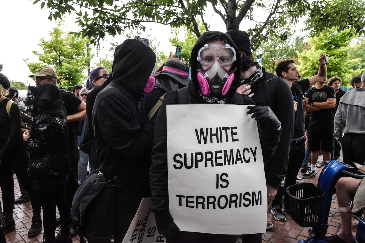 Members of Antifa hold up signs.