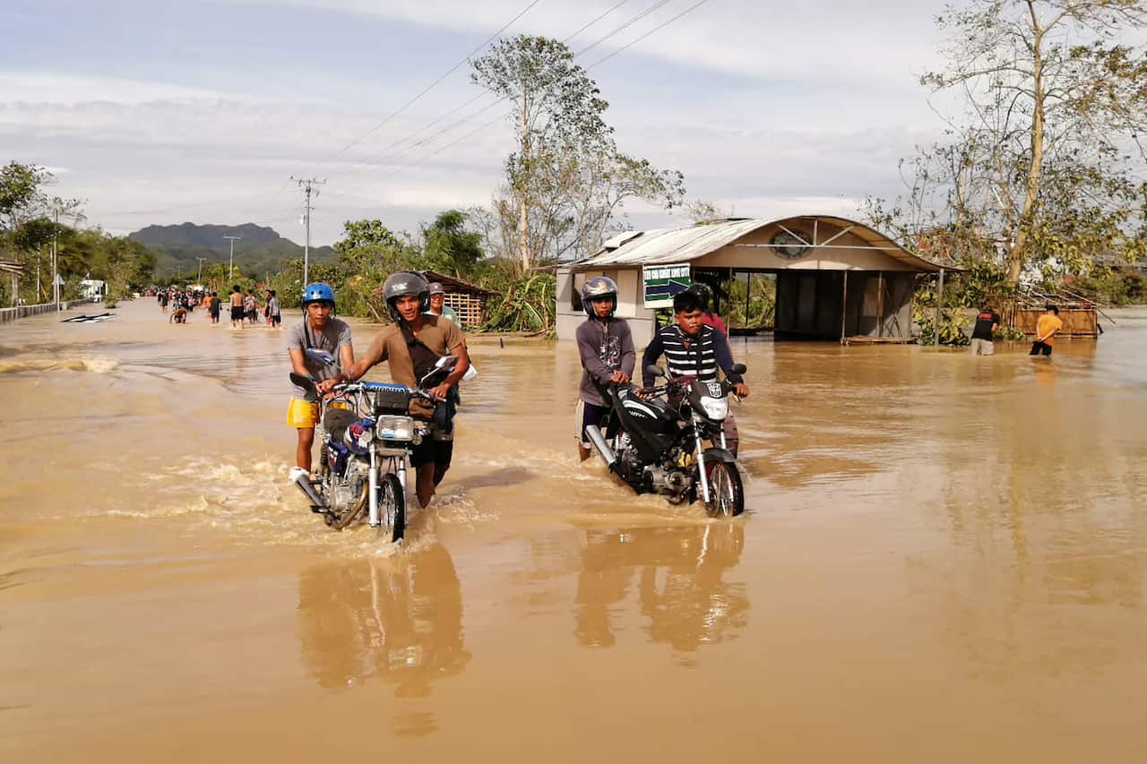 Motorists wade through a flooded highway, caused by heavy rains due to typhoon Phanfone, in Ormoc City, Leyte province in central Philippines.