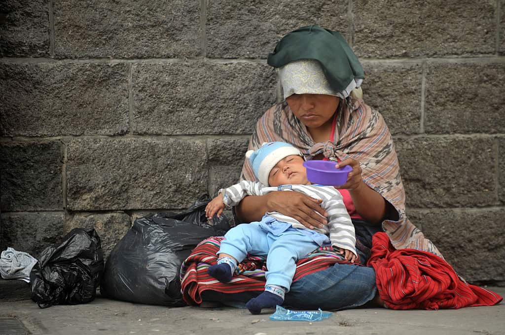 An indigenous woman with her child begs