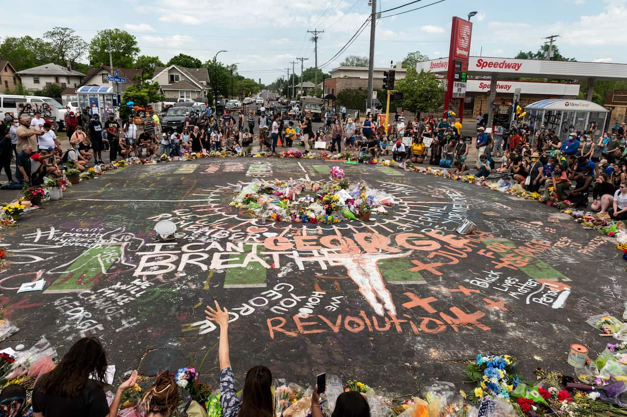 People gather and lay tributes at site where George Floyd died in police custody.