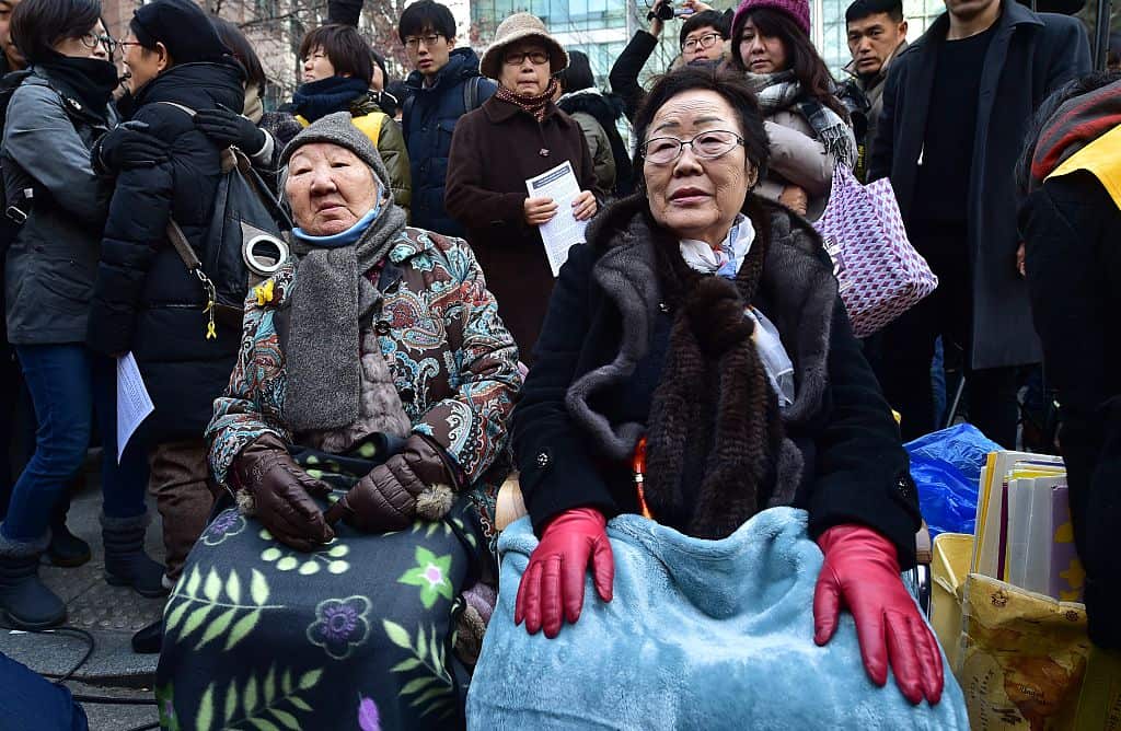 South Korean former 'comfort women' Lee Yong-Soo (r) and Gil Won-Ok (c), who were forced into wartime sexual slavery for Japanese soldiers, sit during a rally commemorating the death of nine former sex slaves this year