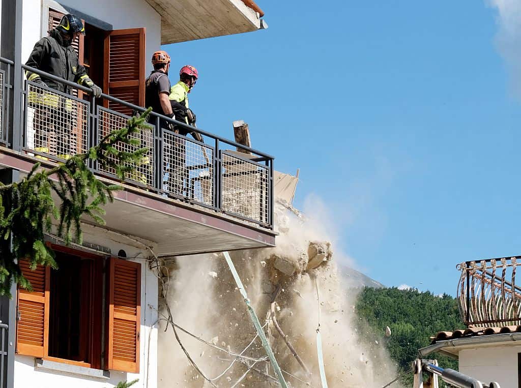 Firefighters knock down rubble which was hanging precariously from an earthquake damaged building in the central Italian village of Illica, near Accumoli.