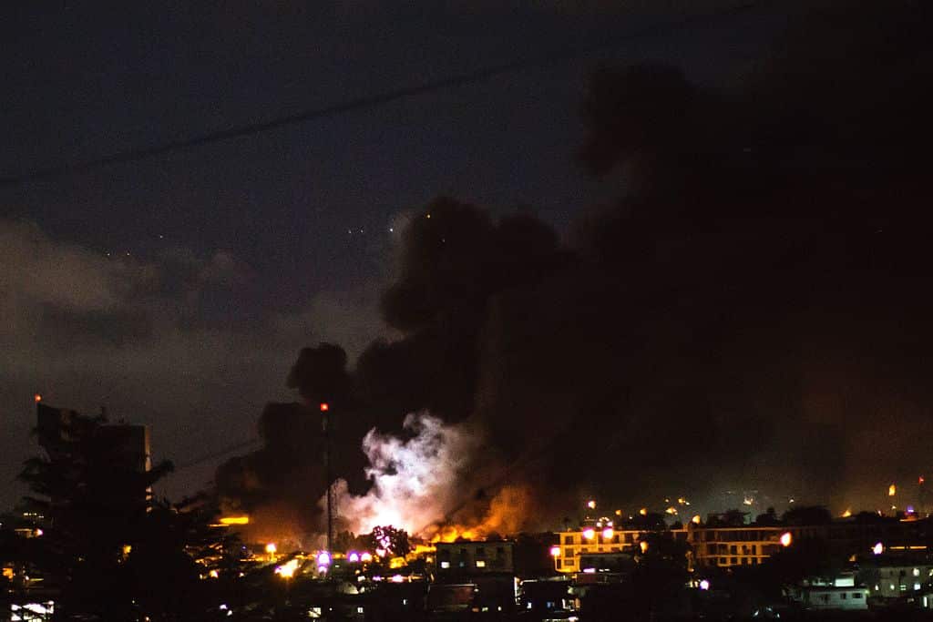 The flash of an explosion is pictured amid flames and smoke billowing from the National Assembly building in Libreville 