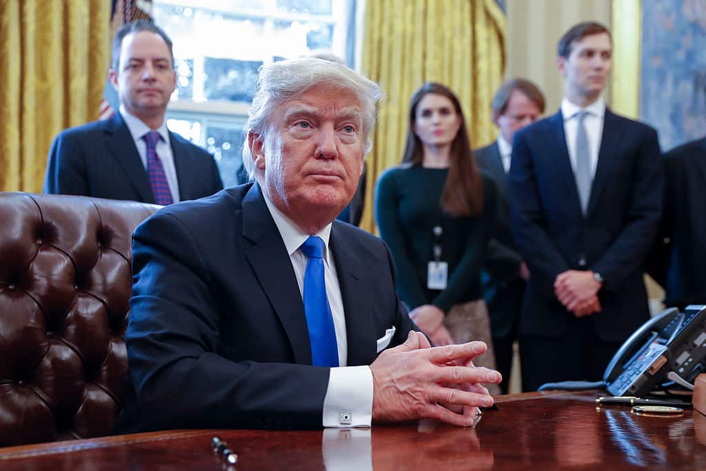 President Donald Trump looks on after signing one of five executive orders related to the oil pipeline industry in the Oval Office of the White House January 24, 2017 in Washington, DC. Also pictured are White House Chief of Staff Reince Priebus (L).