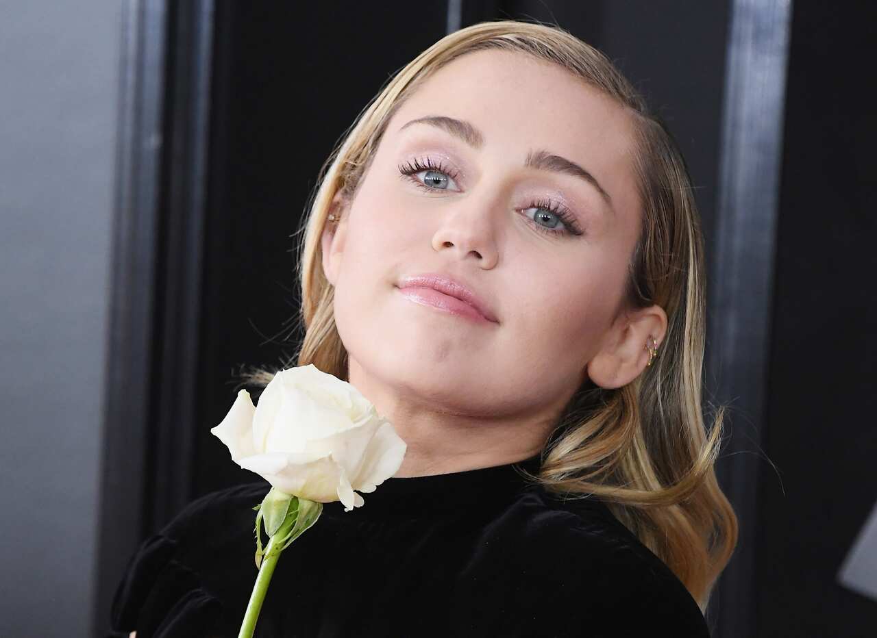 Miley Cyrus brought a white rose to the red carpet at the Grammys.