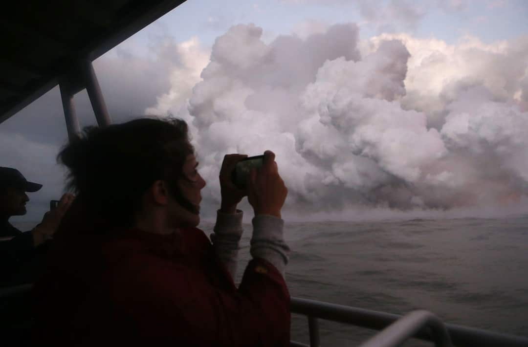 A woman takes photos while riding a tour boat in Hawaii.