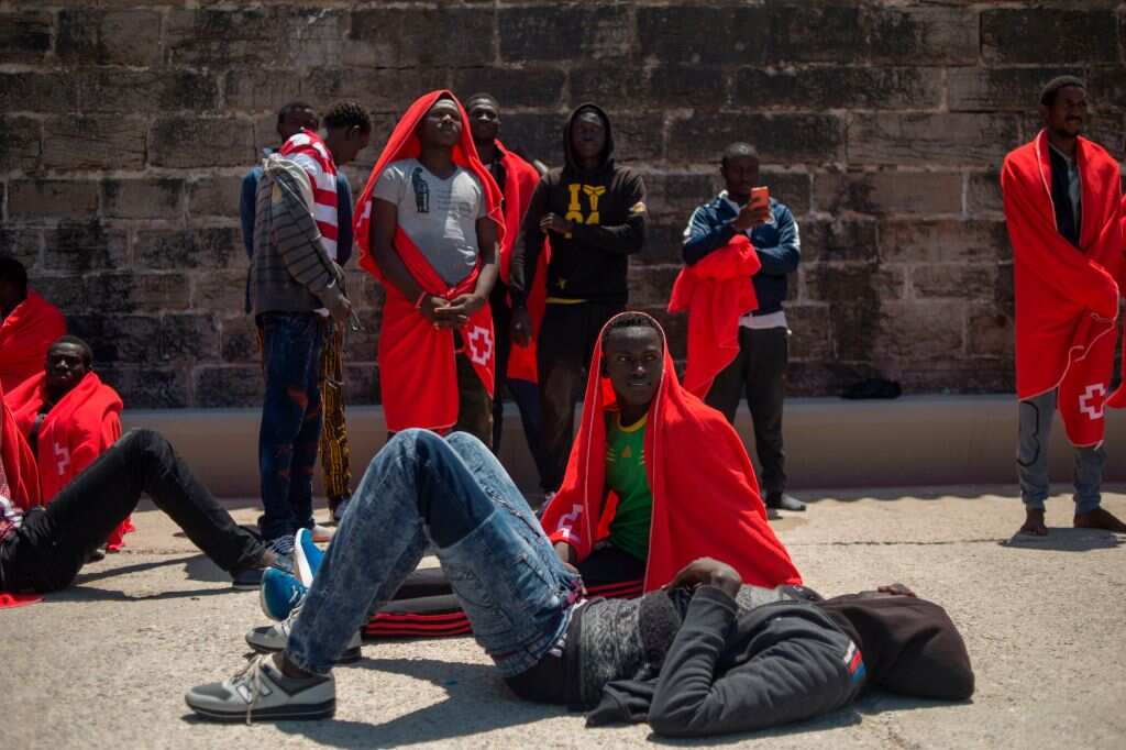 Migrants keep warm wrapped in Red Cross blankets after arriving aboard a coast guard boat at Tarifa's harbour on July 14, 2018.