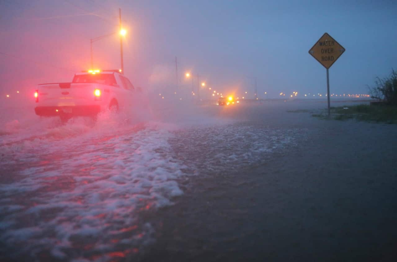 Trucks with the Alabama Department of Transportation work to block off a flooded part of US Highway 98 while fighting rain from Tropical Storm Gordon