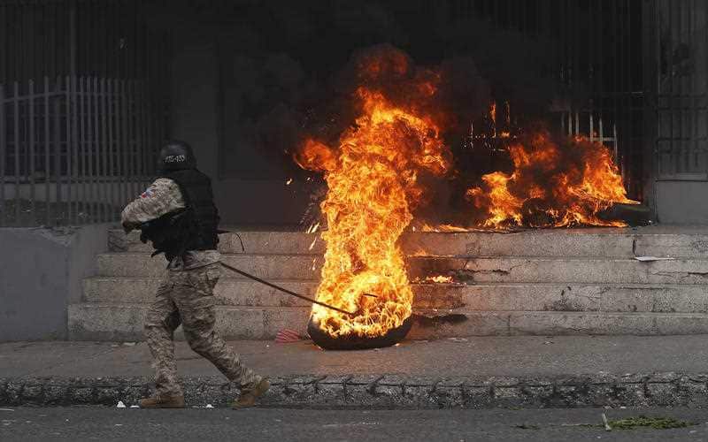 A National police officer removes a burning tire from a government building that was set by anti-government protesters.