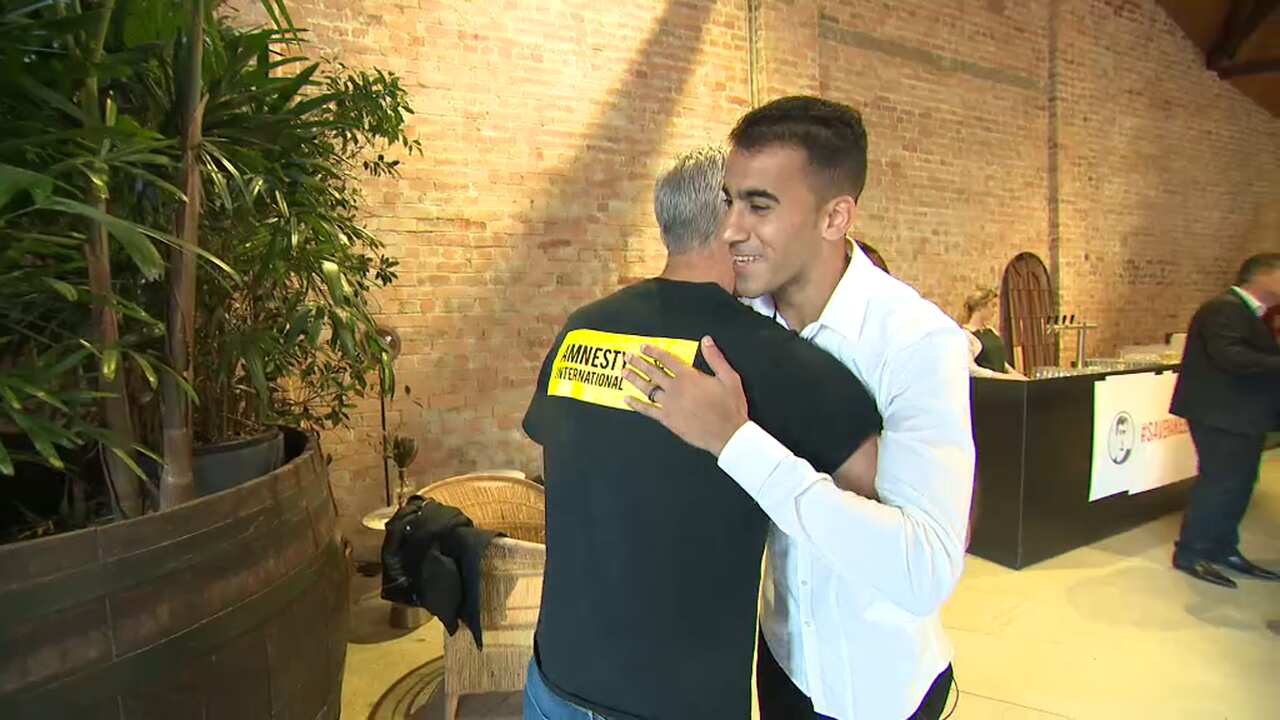 The refugee footballer shares a hug with former Soceroo Craig Foster.