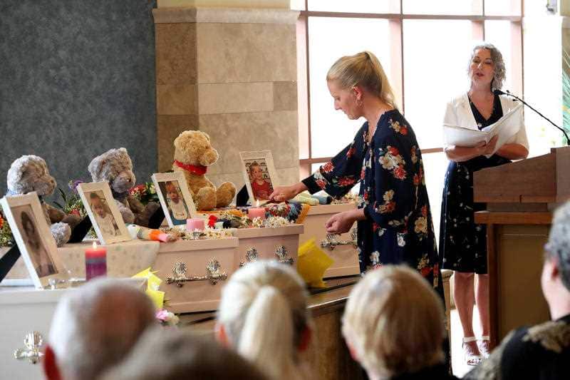 Taryn Tottman lights candles on the coffins of her mother Beverley Quinn, her sister Mara Harvey and Mara's daughters, Charlotte, Alice, and Beatrix.
