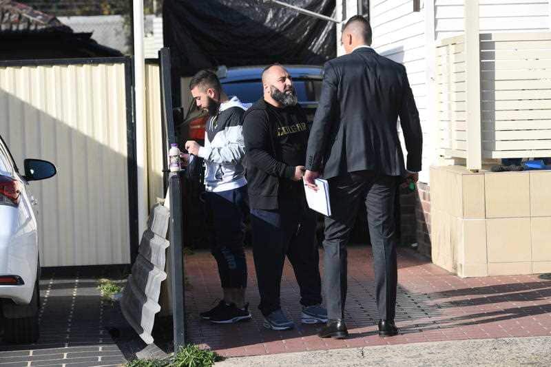 Detectives speak with a man during their search of a home in  Beverly Hills, Sydney.