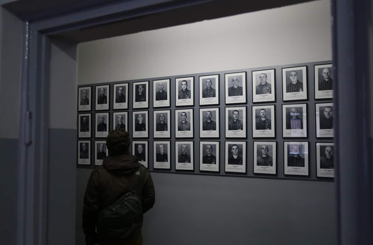 A visitor examining one of the many portraits of murdered prisoners, which line the corridor of Block Six at Auschwitz I