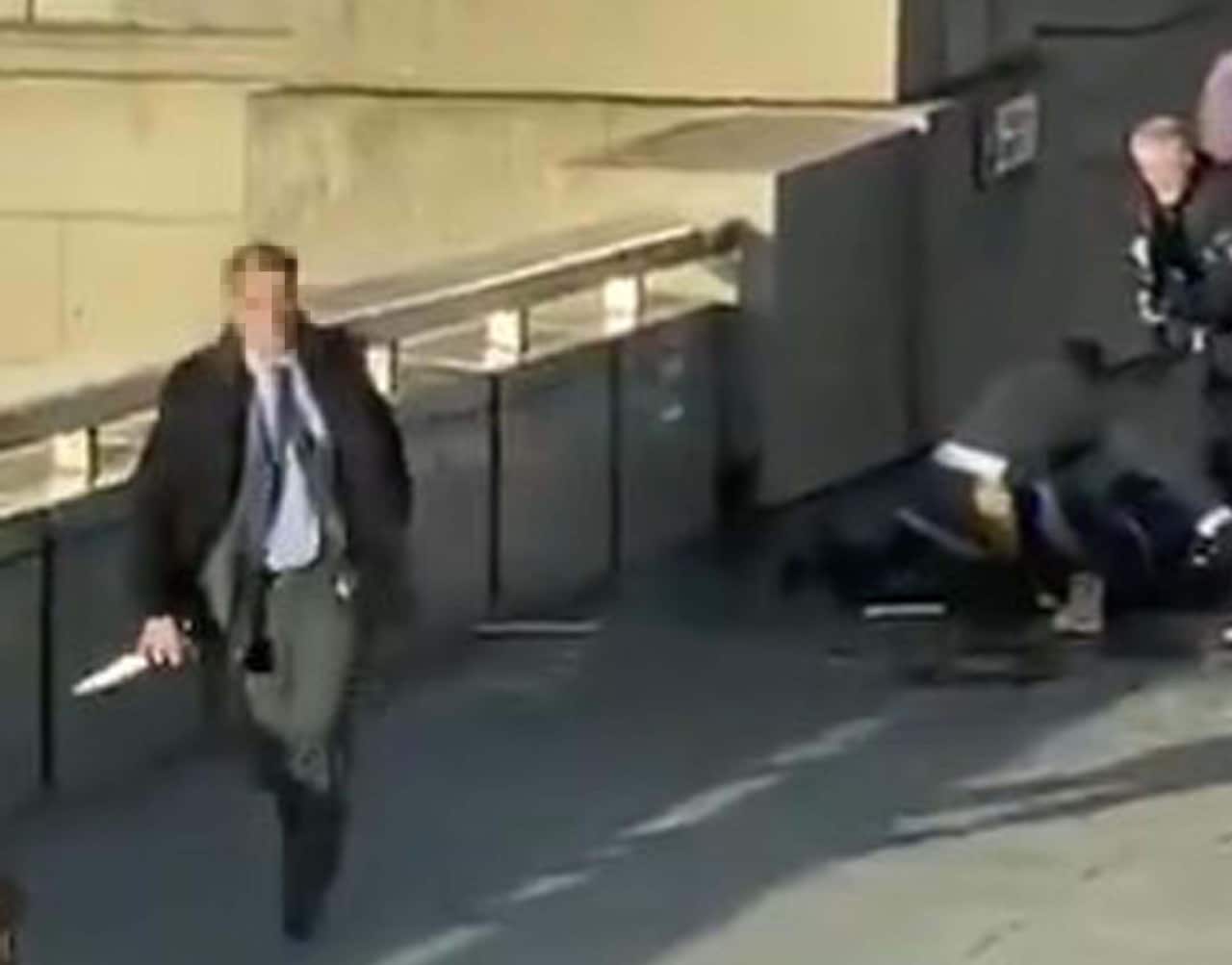 A passerby picks up the attacker's knife and moves it away as armed police move in for the arrest.