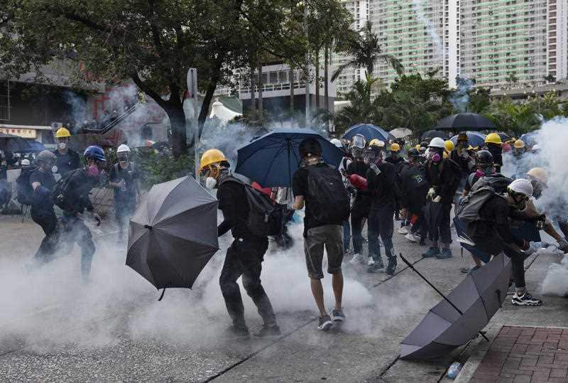Protesters take cover as police and security forces fire tear gas during clashes in Hong Kong.