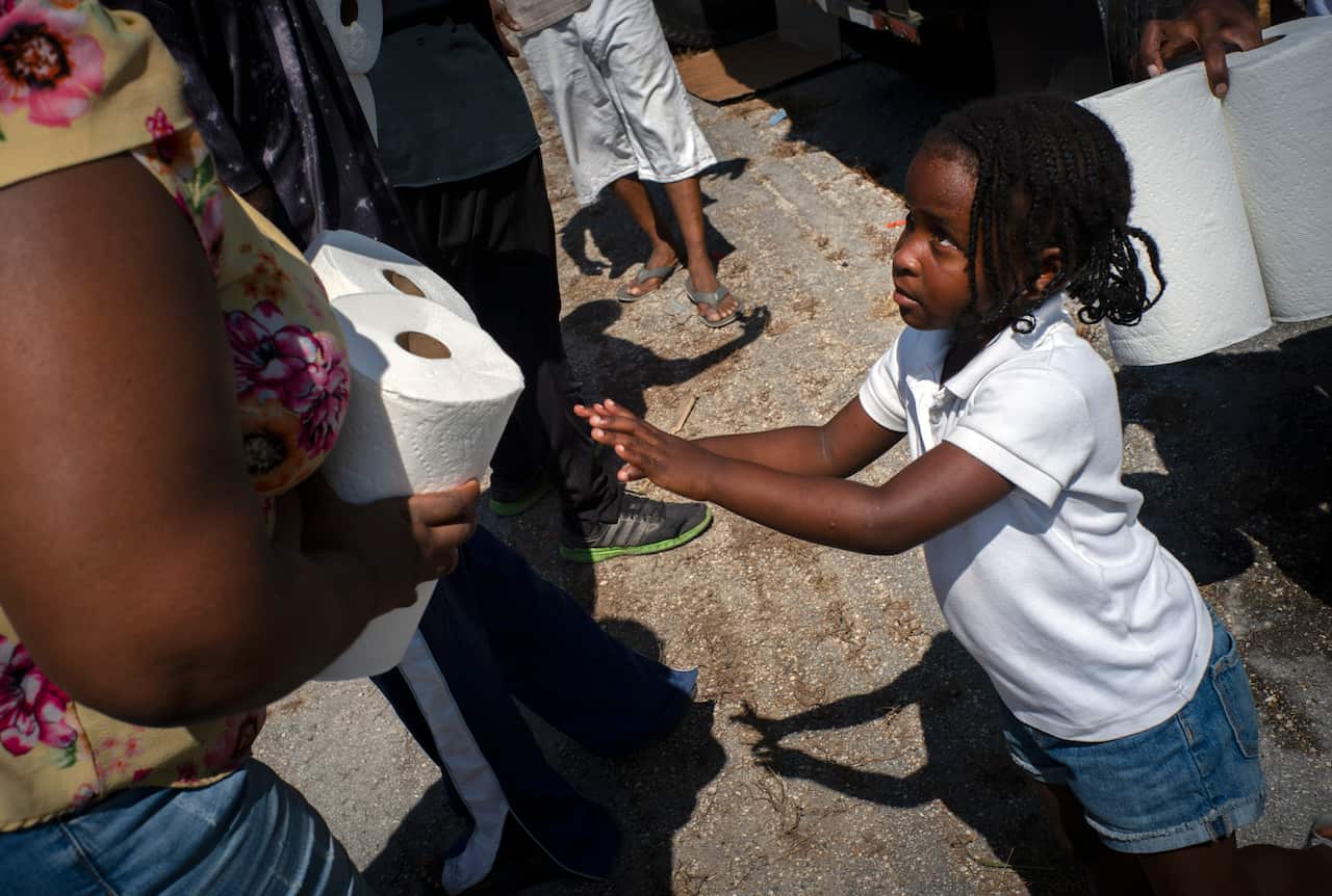 Five-year-old Cattleya Aranha helps to distribute paper rolls donated by private entities to victims of Hurricane Dorian.