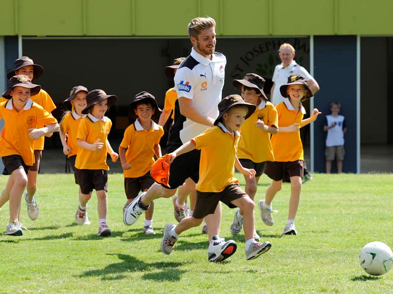 Brisbane Roar midfielder Luke Brattan pays with school children