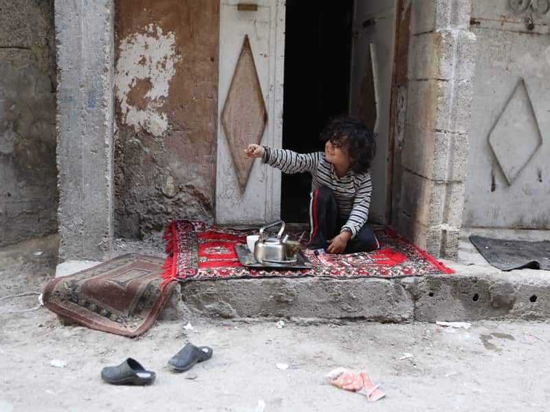 A Syrian boy sits in front of his home  after a ceasefire