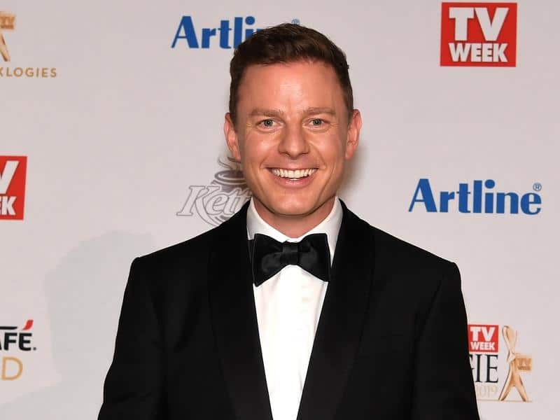 A man in a tuxedo smiles.
