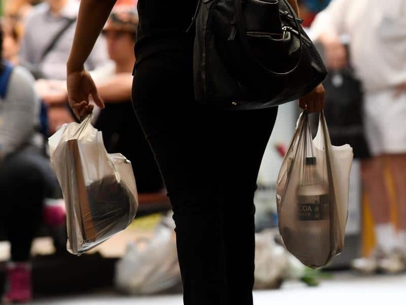 A customer holds plastic supermarket shopping bag.