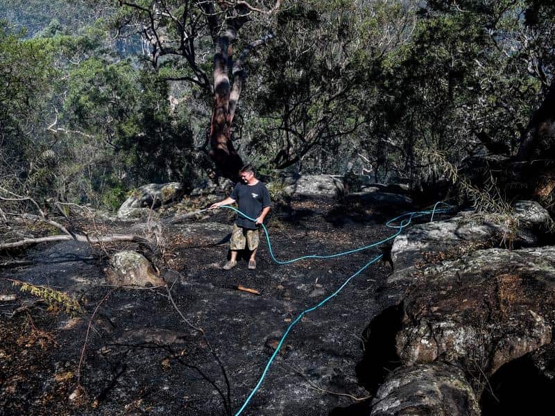 Resident Justin Frith hoses down an area behind his home
