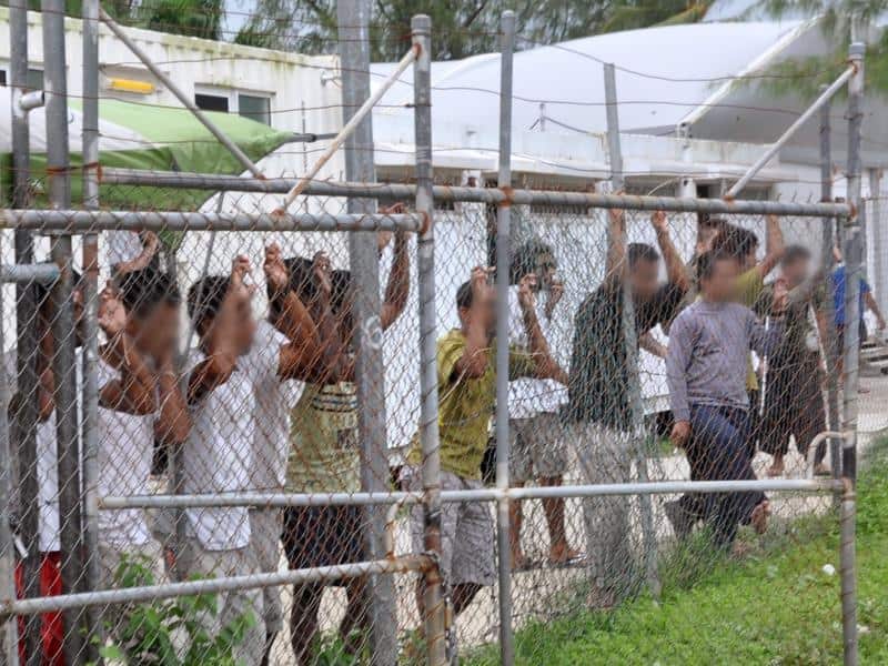A group of asylum seekers behind a fence at a compound in PNG.