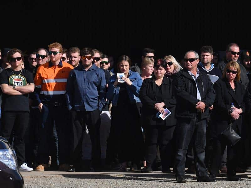 Mourners watch the hearses drive away at the funeral.