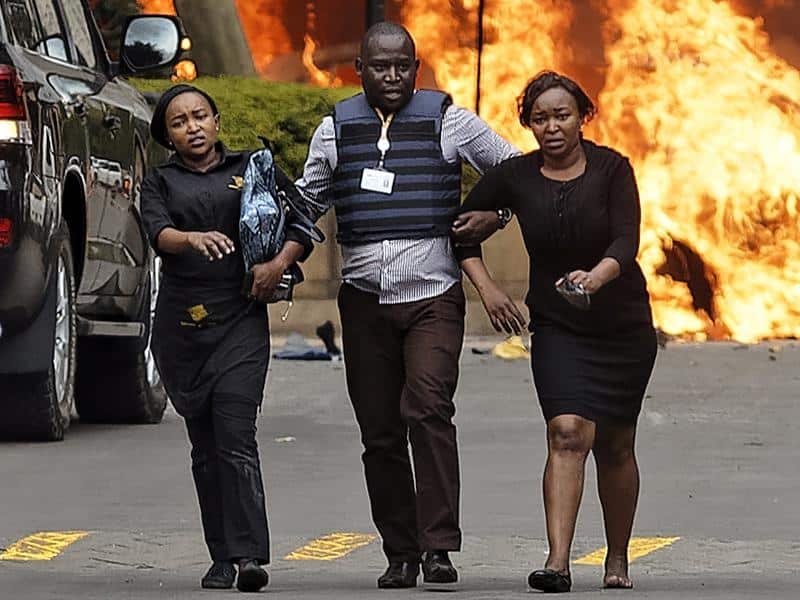 A member of Kenya's security forces helps civilians.