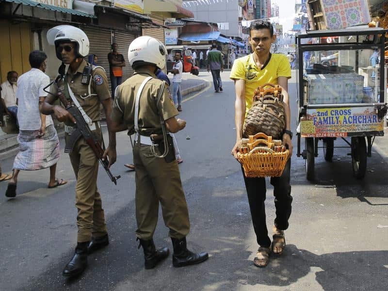 Sri Lankan police officers patrol a street outside a mosque