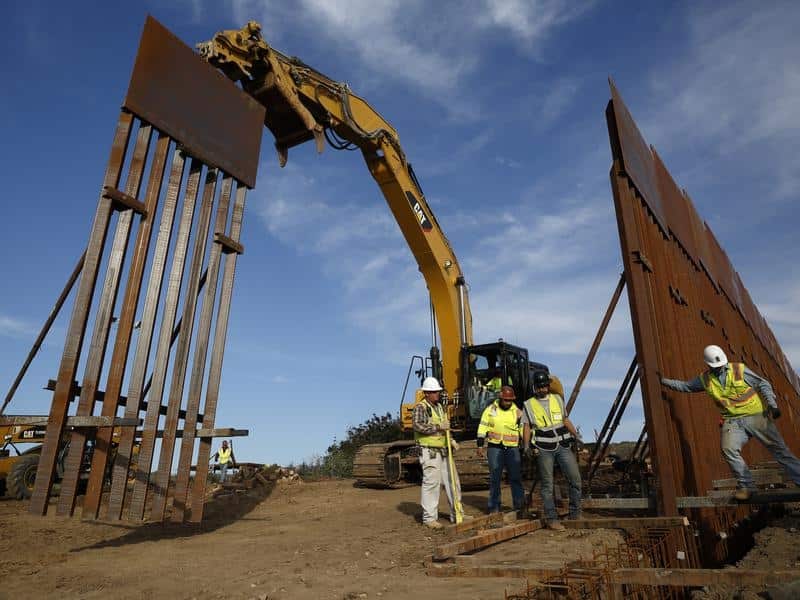 Construction crews install new border wall sections seen from Tijuana.