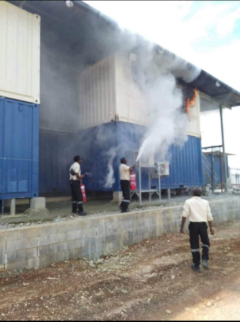 Police and immigration officers can be seen extinguishing the fire at the Manus Island compound.