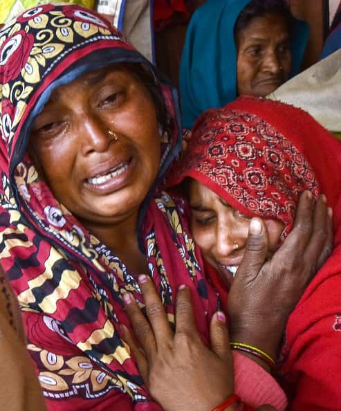 Relatives of victims who died from toxic locally-made alcohol cry as their loved ones' bodies are taken away by authorities.