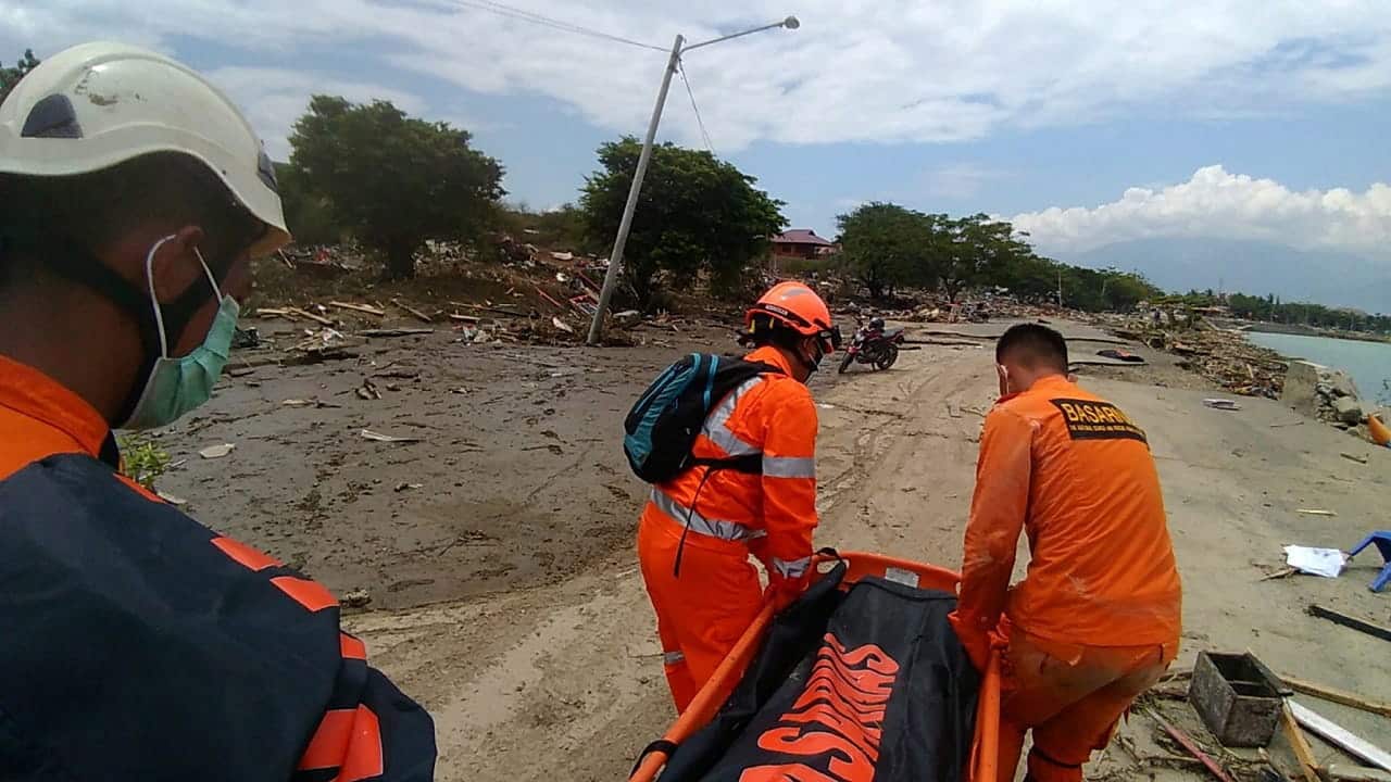 Rescuers from Indonesian National Search and Rescue Agency (BASARNAS) move bodies of the victims at Wina beach.