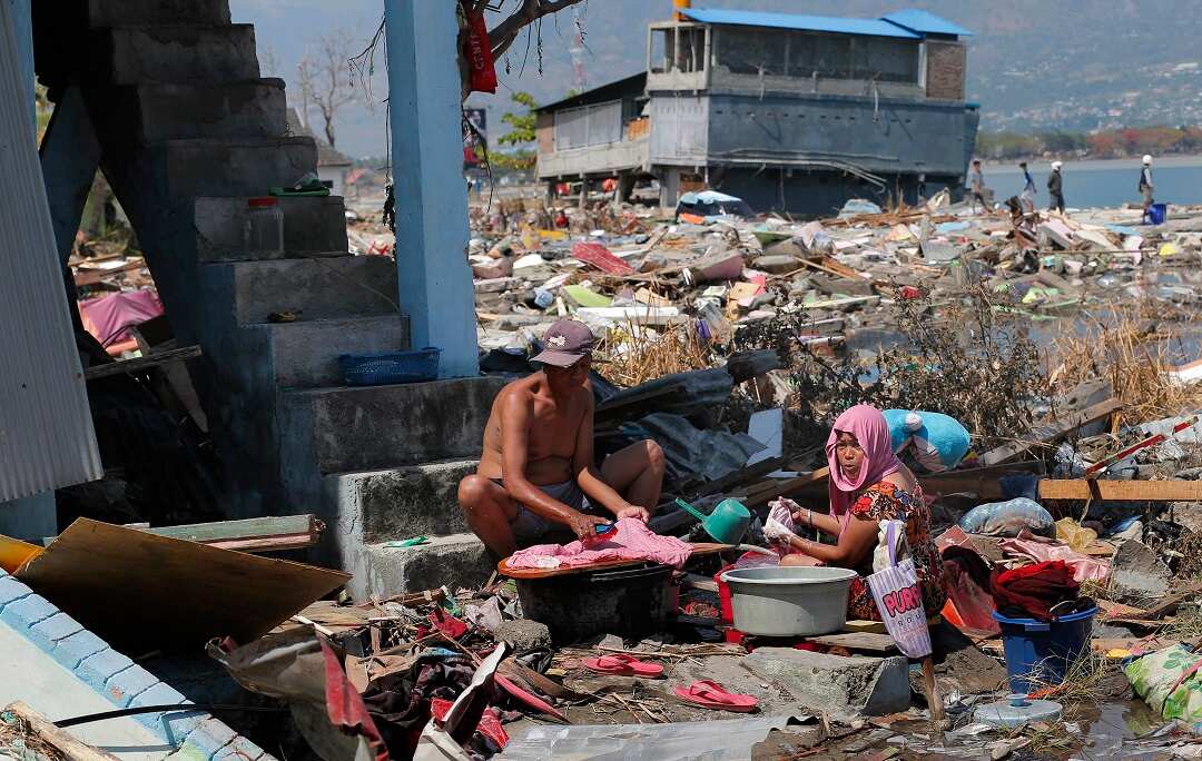 Villagers wash clothes amongst the rubble. 