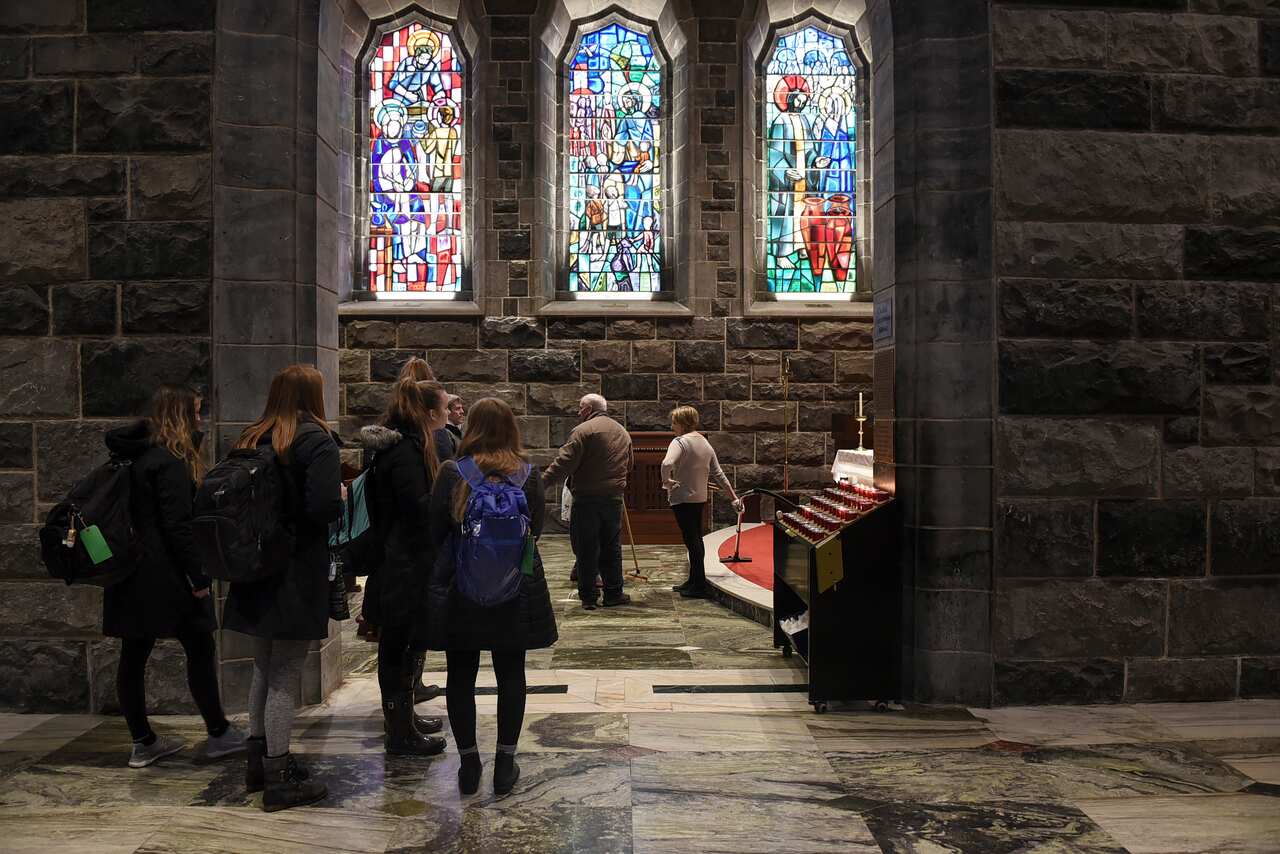 A group of schoolgirls look around Galway Cathedral as a team of cleaners pause for a break, in Galway, Ireland.