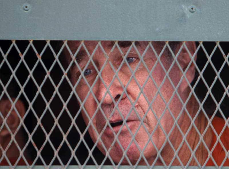 James Ricketson talks from inside a prisoner truck upon his arrival at Phnom Penh Municipal Court in Phnom Penh, Cambodia.
