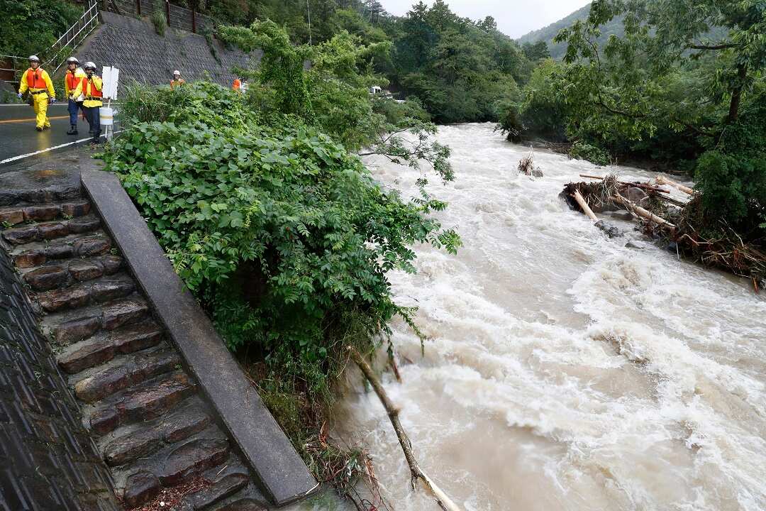 Rescuers search for a missing person near a river swollen by a heavy rain in Osaka, western Japan.