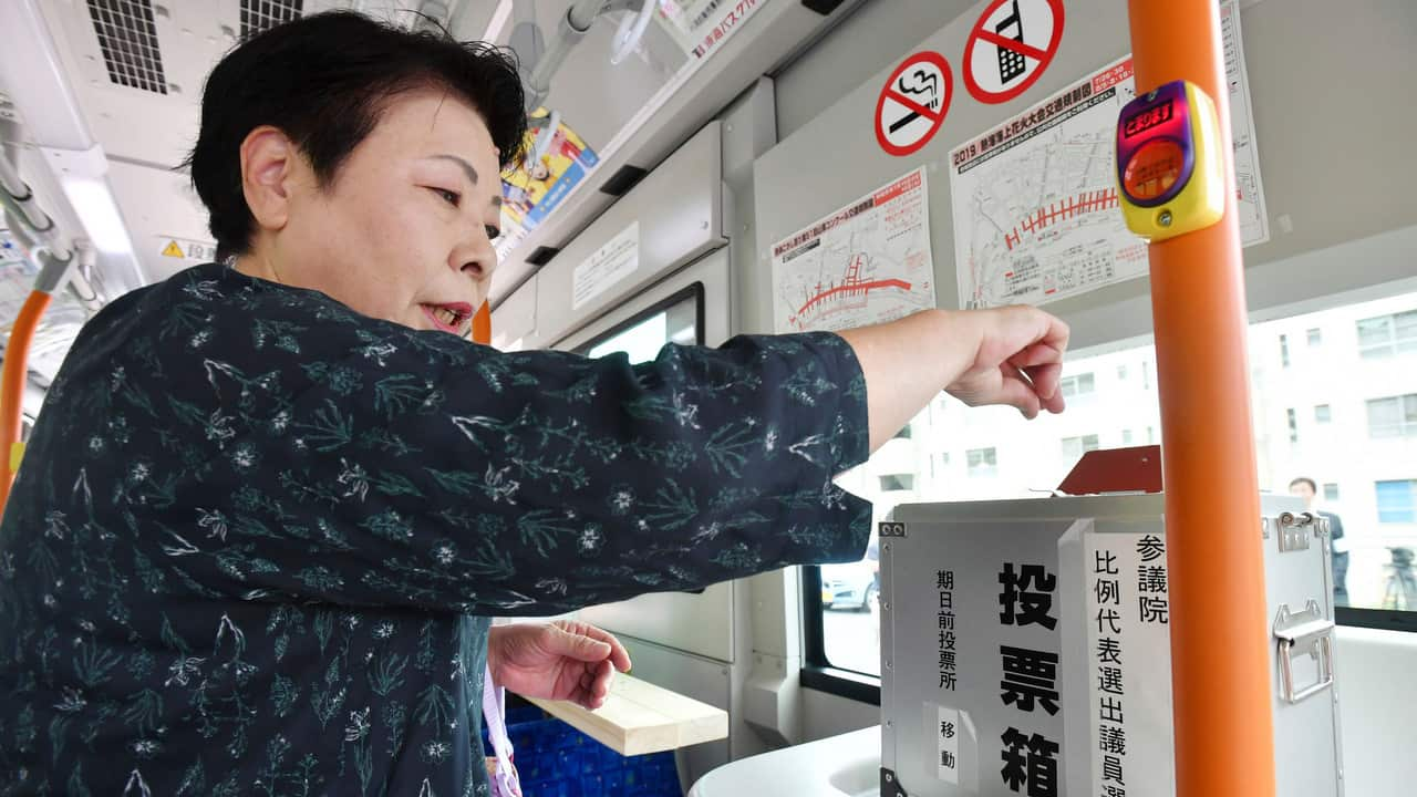 A resident casts her vote into a balloting box on a fixed route bus operating in the mountain district in Atami, Shizuoka Prefecture.