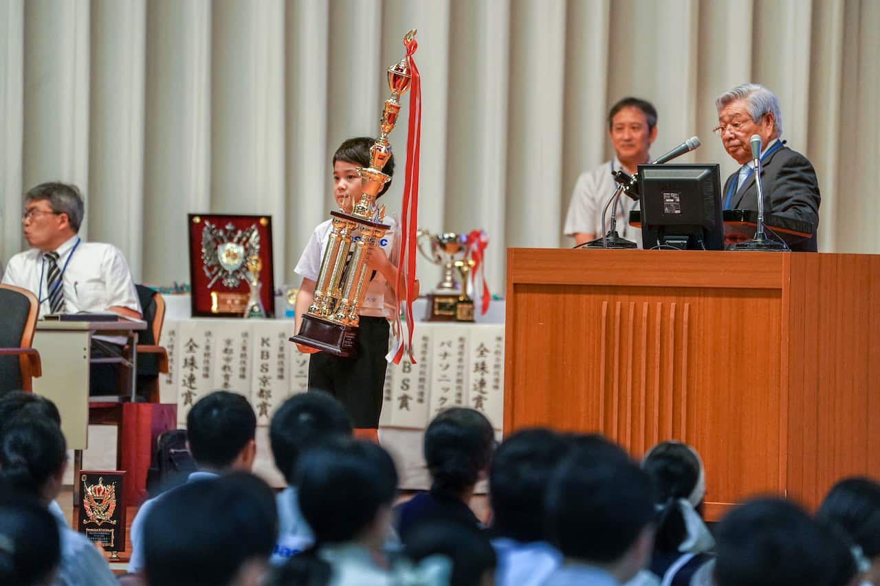 Kota Ginama, 11, of Okinawa, after receiving a trophy from Kazutaka Hirakami, right, chairman of the league for Soroban Education of Japan, for winning the individual category among elementary school students in Kyoto, Japan, on Aug. 8, 2019. It was Ginam