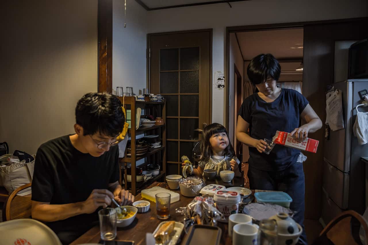 Kazuko Yoshida puts socks on her daughter as she watches television, in Tokyo.