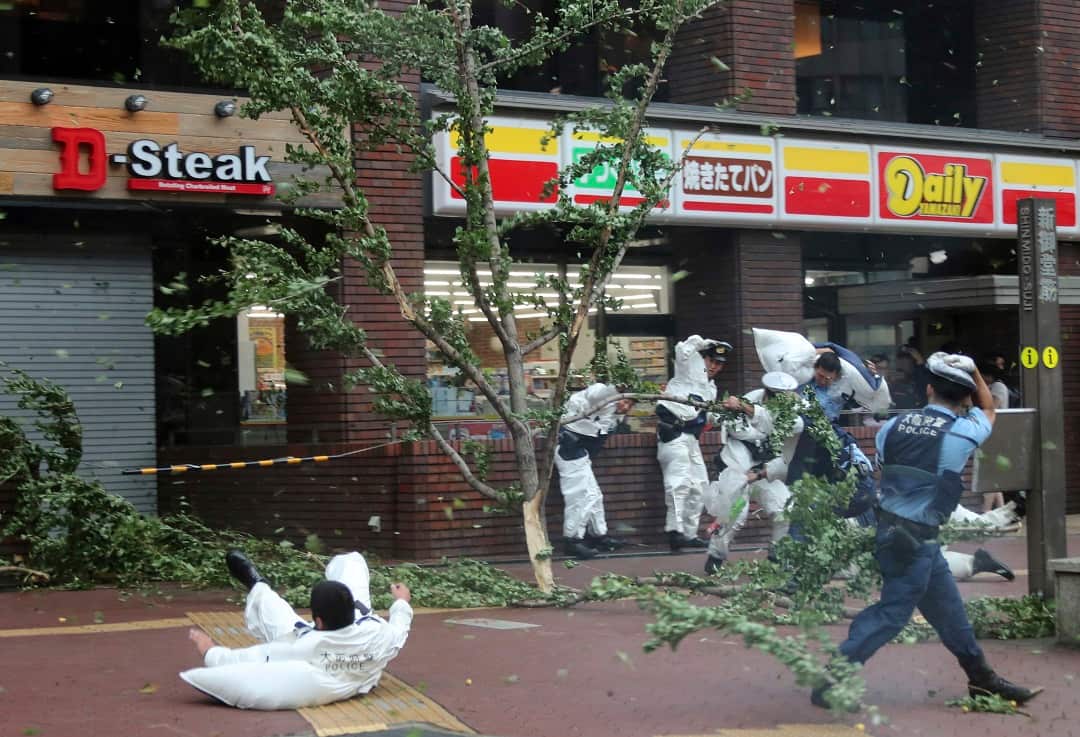 A police officer falls over in strong winds triggered by typhoon Jebi.