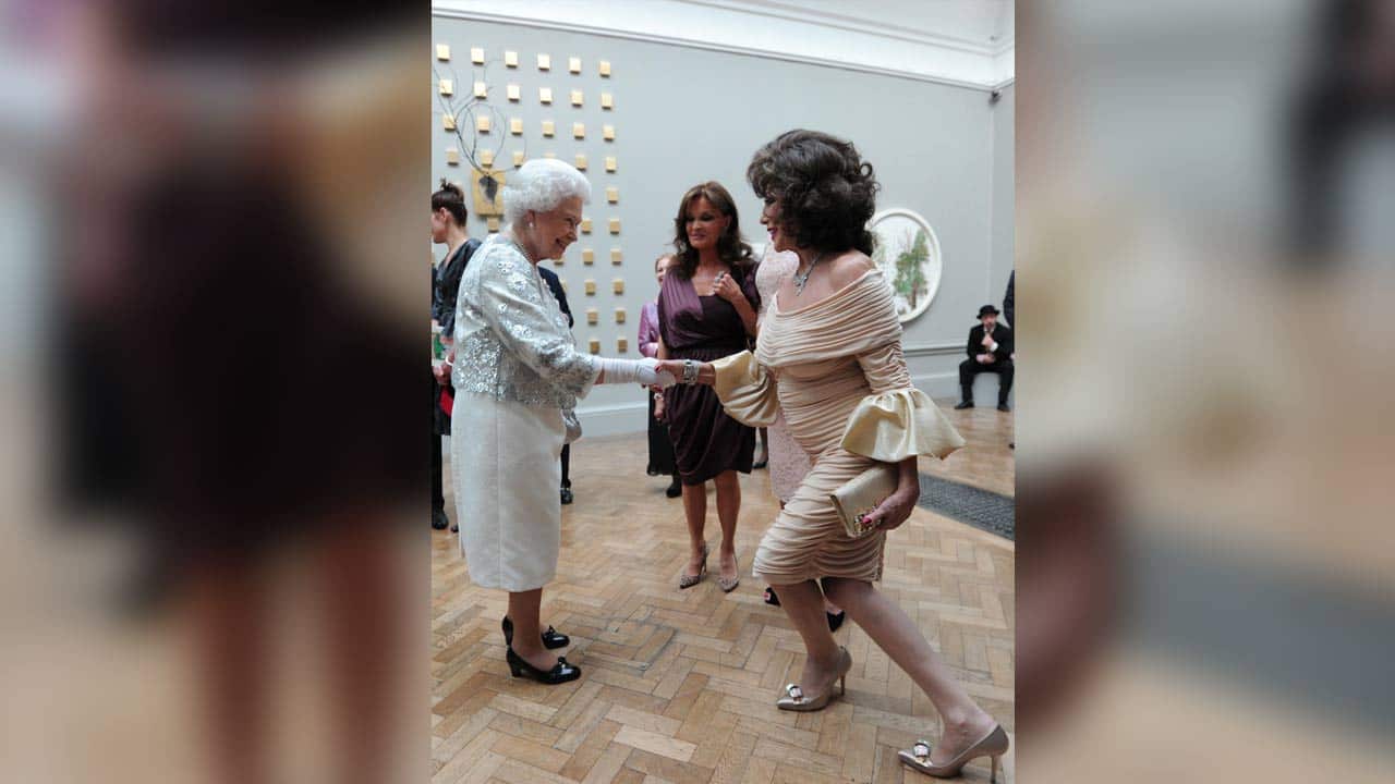 Joan Collins curtsying as she meets Queen Elizabeth II during a Diamond Jubilee celebration