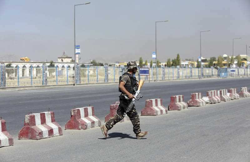 An Afghan security officer runs toward a house where attackers are hiding, in Kabul, Afghanistan. Fresh fighting has broken out in the capital.