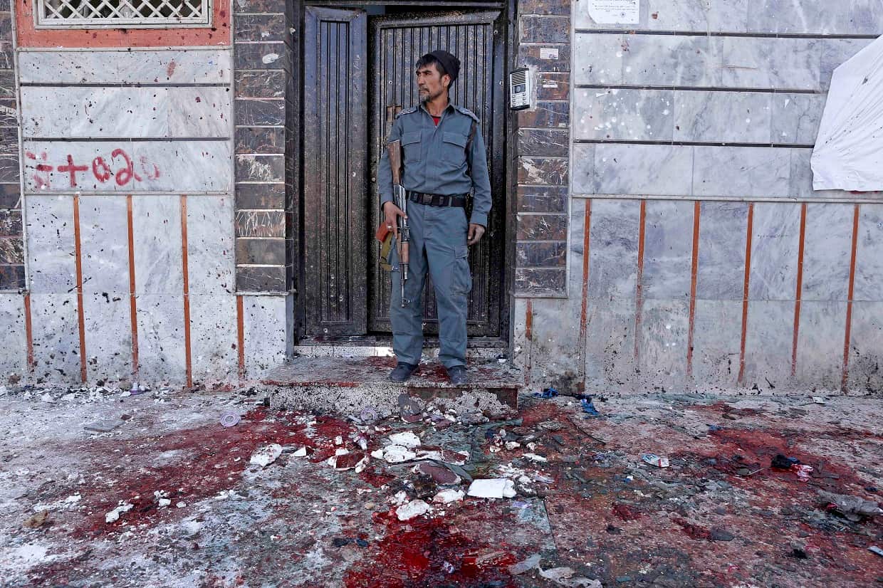 An Afghan police officer inspects the scene of the suicide bomb attack.