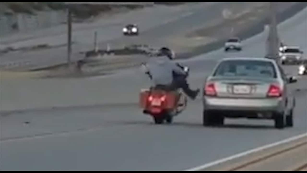 The moment the motorcyclist 'kicks' the silver sedan