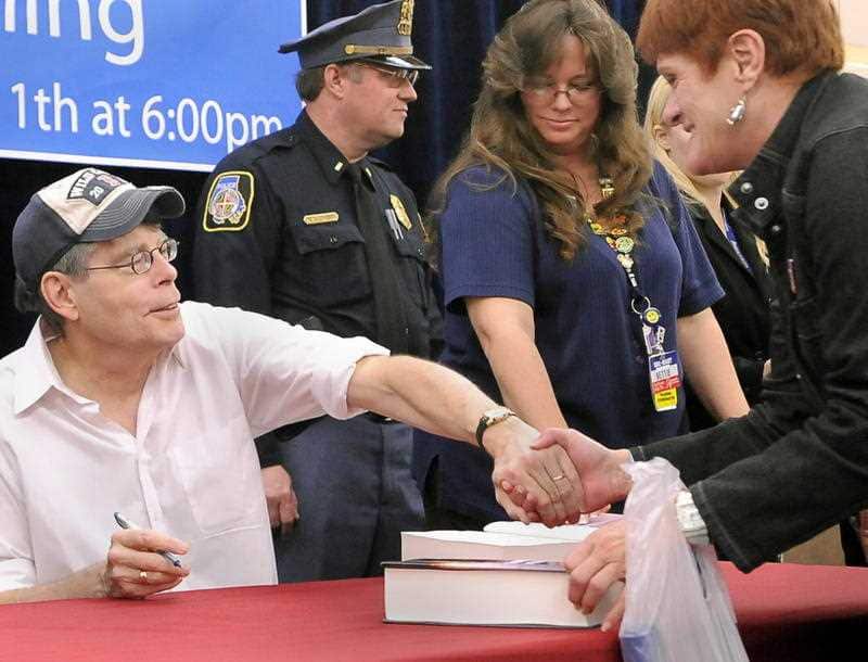 Author Stephen King shakes hands with a fan as she buys his book, "Under the Dome".